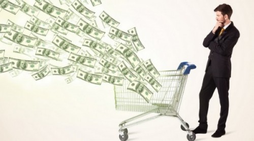 Businessman pushing a shopping cart and dollar bills coming out